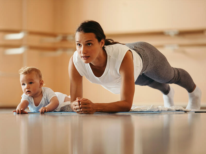 Postpartum rehab mom performing plank with infant